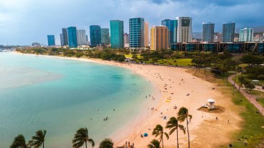Temiz turkuaz suyu olan lüks kumlu bir sahil. İnsanlar Waikiki, Hawaii, ABD 'de Pasifik Okyanusu kıyısında dinleniyor. Hava görünümü.