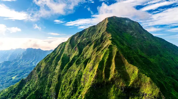 Güneş ışığında yemyeşil kayalar. İnsansız hava aracı Hawaii, ABD 'deki bir dağdan uzaklaşıyor..