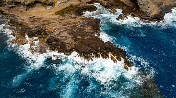 Su sıçratan okyanus dalgalarının oluşturduğu çıplak kayalar. Kıyı üzerinde deniz suyu fışkıran hava perspektifi. Hava görünümü.