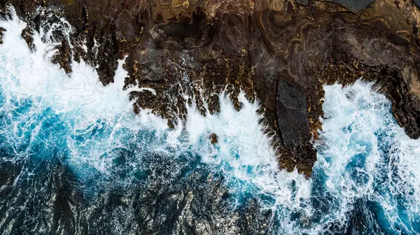 Kayalara vuran köpüklü dalgaların hoş manzarası. Okyanusun kayalık sahillerine hava perspektifi.