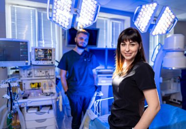 Modern bir klinikteki tıp uzmanları. İki sağlık personeli, sağlık prosedürü sırasında iyi aydınlatılmış bir tedavi odasında güven içinde poz verirler..