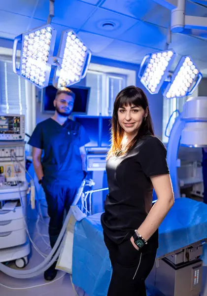 Cerrahi odasında tıbbi uzmanlar var. İki sağlık çalışanı modern cerrahi ortamda güvenli bir şekilde poz veriyorlar, gelişmiş ekipmanlarla bir prosedüre hazırlar..