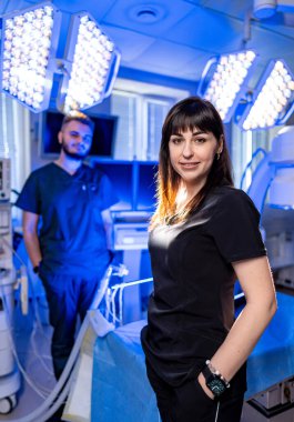 Cerrahi tıbbi personel. İki tıbbi personel, ekipmanlarla dolu, parlak ve gelişmiş bir ameliyathanede ameliyata hazırlanıyor..