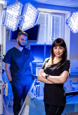 Modern ortamlardaki cerrahlar. İki sağlık çalışanı iyi donanımlı bir ameliyathanede ameliyata hazır bekliyor..