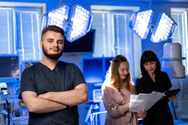 Doktorlar birlikte çalışıyor. Genç doktorlar iyi aydınlatılmış bir hastane odasında hasta bakımını tartışıp belgeleri gözden geçiriyorlar..