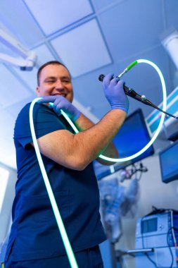 Klinikte cerrah hazırlık aletleri. Bir doktor endoskopla parlak bir klinik ortamda gülümser, muayene için hazırdır..