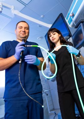 Doktorlar işleme hazır. Önlüklü iki sağlık çalışanı modern bir tıp odasında, bir prosedür için aletler hazırlıyorlar..