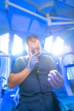 Doktor endoskopi aletlerini kontrol ediyor. Bir tıp uzmanı, endoskop ekipmanlarını parlak aydınlatılmış bir ameliyathanede inceler ve bir prosedüre hazırlanır..