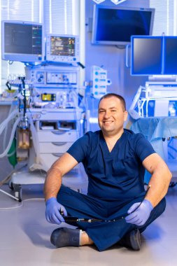 Doktor klinikte dinleniyor. Bir sağlık çalışanı, dost canlısı, iyi donanımlı bir tıbbi odada bacak bacak üstüne atmış bir şekilde oturur..