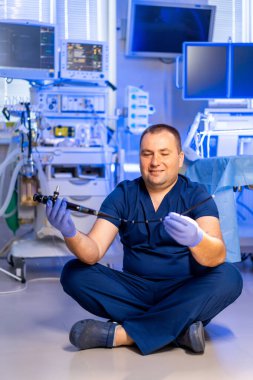 Doktor endoskopiyi klinikte hazırlıyor. Bir tıp uzmanı endoskopla yerde bağdaş kurup ameliyata hazır bir şekilde oturur..