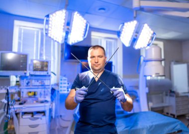 Cerrah ameliyata hazırlanıyor. Kendine güvenen bir tıp uzmanı, iyi donanımlı bir ameliyathanede elinde cerrahi aletlerle bir prosedür bekliyor..