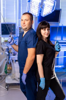 Önlüklü, kendine güvenen profesyoneller. İki tıp uzmanı bir hastanede, cerrahi aletlerle takım çalışması sergiliyorlar..