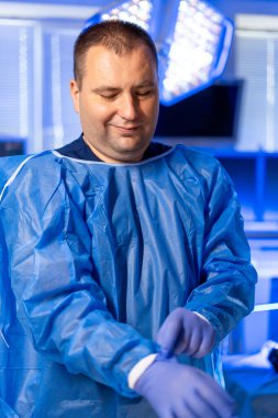 Doktor işleme hazır. Koruyucu teçhizat kullanan bir sağlık çalışanı klinik bir ortamda bir prosedüre hazırlanıyor..