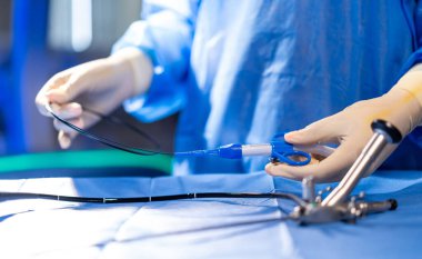 Ameliyathanede aletli bir cerrah. Mavi önlüklü bir sağlık uzmanı ameliyat sırasında steril bir masada cerrahi bir alet hazırlıyor..