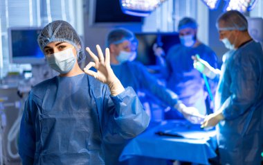 Cerrahlar ameliyatta başarılı olurlar. Modern bir ameliyathanede ameliyat sırasında cerrahi giysi şovu yapan sağlık uzmanları takım çalışması ve beceri..