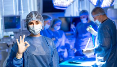 İşbirlikçi sağlık ekibi. Ameliyat sırasında ameliyat önlüğü ve maskeli bir cerrahi ekip modern bir ameliyathanede hasta bakımını sağlamak için işbirliği yapar..