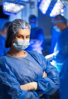 Cerrah ameliyata hazır. Önlüklü odaklı bir cerrah, iyi aydınlatılmış bir ameliyathanede hayati bir tıbbi operasyon için hazır bekliyor..