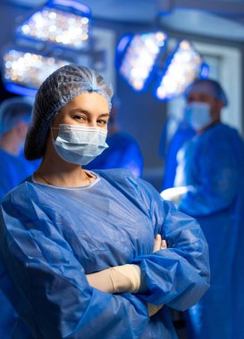 Cerrahi tıp uzmanı. Kendine güvenen bir tıp uzmanı cerrahi giysiler içinde modern bir ameliyathanede bir sonraki işleme hazırlanıyor..