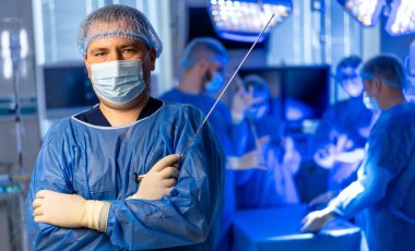 Cerrahlar ameliyathanede takım oluşturun. Mavi önlüklü cerrahlar modern ve parlak bir ameliyathanede gelişmiş tıbbi ekipmanlarla bir prosedür uyguluyorlar..