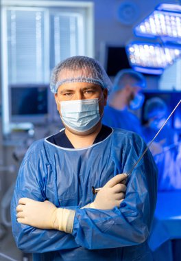 Cerrah ameliyata hazırlanıyor. Bir cerrah, yüksek teknolojili bir hastanede karmaşık bir operasyona yardım etmek için cerrahi kıyafetlerle güvenle ayakta durur..