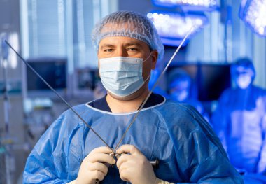 Cerrah ameliyata hazır. Cerrah modern bir ameliyathanede karmaşık bir prosedür başlatmak için aletlerle hazır bekliyor..