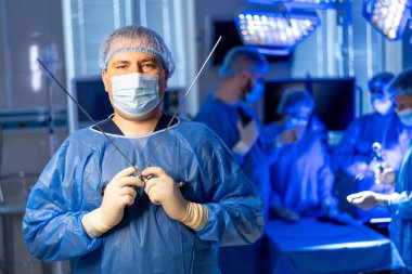 Ameliyathanede ameliyat ekibi var. Cerrahi bir ekip, öncü cerrah aletleri tutarken parlak ışıklı bir ameliyathanede ameliyat yapıyor..