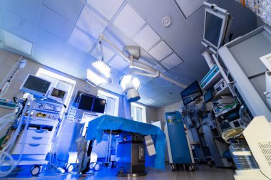 Modern cerrahi odası düzeneği. Ameliyat masası, tıbbi cihazları ve parlak ışıklandırması olan yüksek teknolojili bir ameliyathane..