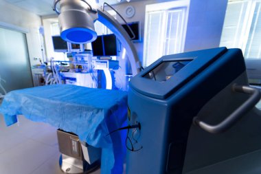 Ameliyathane hazır. Modern ameliyathane tıbbi ekipmanlar, mavi cerrahi perdeler ve ameliyat için görünür gelişmiş teknolojiyle donatılmış..