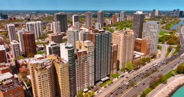 Birbirine yakın yüksek binalar sırasına yaklaşıyorlar. Birçok araba Chicago, Illinois, ABD otobanlarından geçiyor..