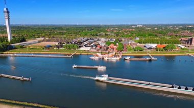 Dolu olmayan mavnalar, barajlar boyunca sakin sularda yüzer. Lelystad, Hollanda, Batavialand Müzesi ve Telekom Kulesi 'nin göl manzarası.