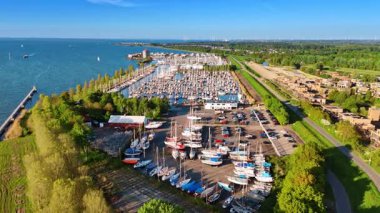 Otoparkın yakınındaki sahildeki teknelere yaklaşıyoruz. Yat kulübünün sunucusunda sayısız yat var. Hollanda, Lelystad 'ın yeşil şehir manzarası.