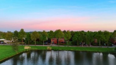 Pahalı yeşil köyün yakınındaki gölet üzerinde hızlı bir uçuş. Hollanda, Vinkeveen 'de gün batımı.