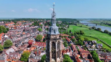 Güneşli bir günde güzel bir saat kulesinin tepesinde uçmak. Rhenen 'deki Cunera Kilisesi, Utrecht ili, Hollanda. İnsansız hava aracından güzel bir şehir manzarası.