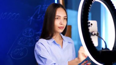 Gömlekli güzel, koyu saçlı, beyaz kadın cam duvara yazılı rakamlar gösteren video kaydı yapıyor. İçerideki günlük görüntüleri.