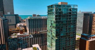 Chicago, Illinois, ABD merkezindeki yüksek katlı cam bir binaya yaklaşıyoruz. Arka planda Michigan Gölü.