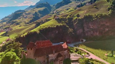 Runkelstein Kalesi ve nehir çiçeğinin üzerinde uçuyor. Resimli dağların yamaçlarını kaplayan üzüm bağlarının nefes kesici manzarası. Bolzano, Güney Tyrol, İtalya. Hava görünümü.