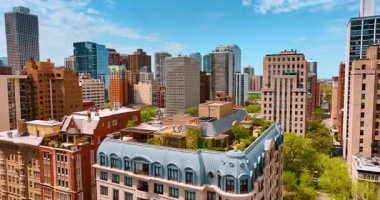 Etrafı yeşil ağaçlarla çevrili binaların üzerinde yükseliyor. Evlerin tepesindeki rahat bahçelerin manzarası. Chicago, Illinois, ABD.