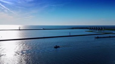 Su yüzeyinde yüzen tekne güneşte parlıyor. Merkemeer Gölü üzerinde barajlar ve kanallarla hava manzarası. Lelystad, Hollanda.