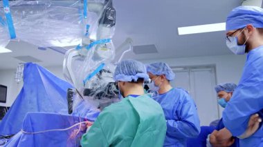 Cerrahlardan oluşan bir ekip beyin operasyonunda çalışıyor. Cerrahlar nöroşirürjide mikroskop kullanır..