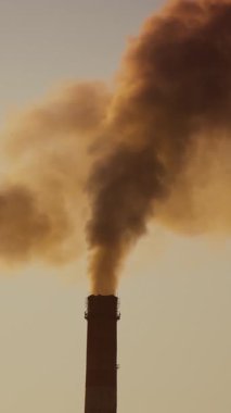 Havada kirli yoğun emisyonlar var. Gün batımında dumanlı iki büyük boru. Ekolojik felaket. Hava kirliliği. Dikey video