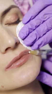 Estetik tıp doktoru müşterinin dudaklarına botoks yapar. Güzellik iğneleri. Kozmetoloji. Yakın plan. Dikey video