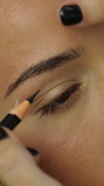 Güzellik salonunda kanepede uzanan bir kadın. Kozmetik uzmanı kalıcı göz kalemi makyajı yapıyor