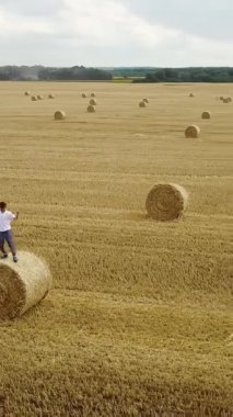 Sahada samanla savaşan bir çocuk. Balyalarla dolu bir tarlada mutlu bir çocuk