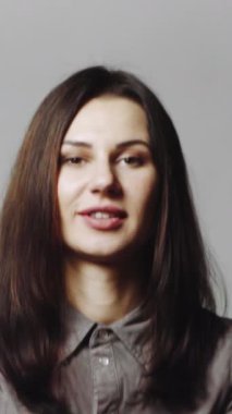 Kadın konfeti üflüyor. Neşeli parti kızı ayakta durup konfeti üflüyor ve kameraya bakıyor.