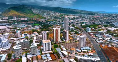 Modern şehir dağların ve yamaçların arasında vadiye dağılmış durumda. Arka planda kara dramatik bulutlar. Hava görünümü.