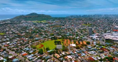 Geniş yerleşim alanının ortasındaki stadyumlar ve mahkemeler. Honolulu, Oahu, Hawaii, ABD üzerinden uçuş. Elmas başlı krater ve Waikiki silueti arkaplanda.