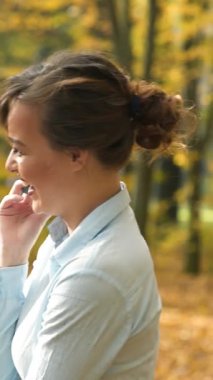 Kadın telefonda konuşuyor. Güz parkında telefonda konuşan çekici bir kadın.