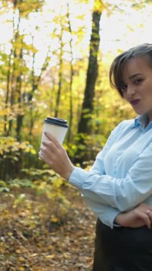 Sıcak çay içen bir kadın. Kadın sonbahar parkında sıcak çayla ısınıyor.