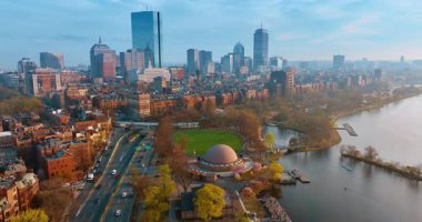 Arabalar Charles Nehri 'nin kıyısındaki parkın yakınındaki yollara gider. Bulutlu bir sonbahar gününde Boston manzarasına hava perspektifi.