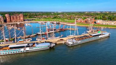 Hollanda 'nın Lelystad limanındaki rıhtımda gemiler, feribotlar ve gemiler. Merkemeer Gölü üzerinde insansız hava aracı uçuşu. Şehrin yeşil manzarasına bir bak..